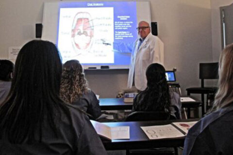 Instructor giving a lesson on oral anatomy to students in a classroom.