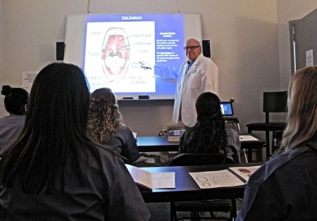 Instructor giving a lesson on oral anatomy to students in a classroom.