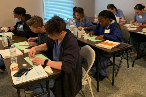 Students seated at tables working on dental training materials.