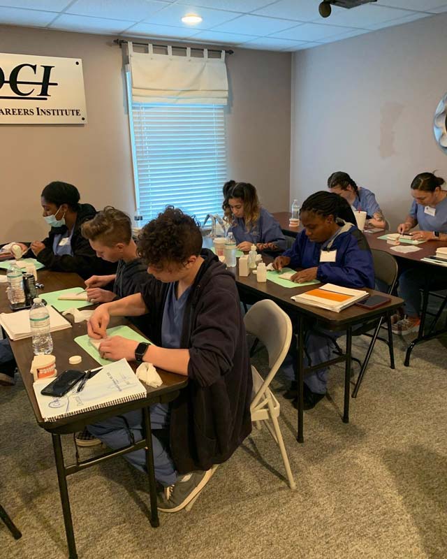 Students seated at tables working on dental training materials.