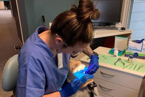 Dental professional practicing a procedure on a training mannequin in a clinic setting