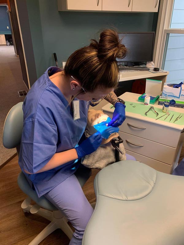 Dental professional practicing a procedure on a training mannequin in a clinic setting
