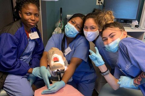 Group of students practicing dental procedures on a training mannequin