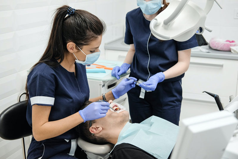 Dental staff attending to a patient during a clinical procedure.