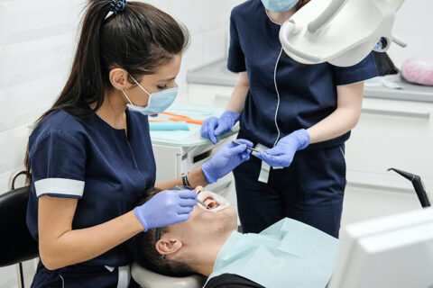 Dental staff attending to a patient during a clinical procedure.